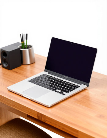 Laptop on a wooden desk with a speaker and a cup of coffee