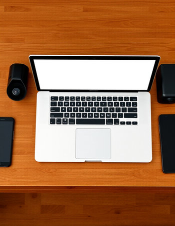 Top view of a desk with a laptop, mobile phone and speaker