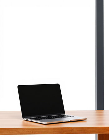 Laptop on a wooden table in front of a window with a white background