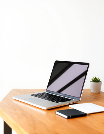 Laptop with blank screen on wood table and white wall background.