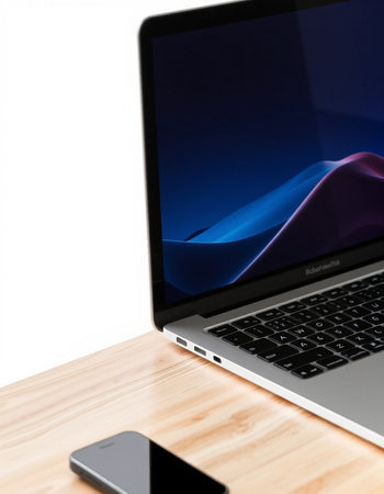 Laptop on a wooden table with a smartphone in the background.