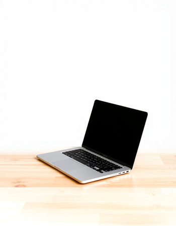 Laptop on wooden table with white wall background and copy space.