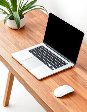 Laptop with blank screen on wooden table and white wall background.