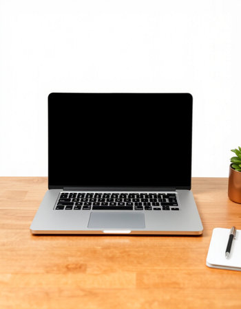 Laptop with blank screen on wooden desk and white wall background.