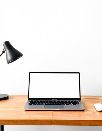 Laptop with blank screen on wooden desk and lamp on white wall background