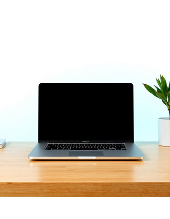 Laptop with blank screen on wooden table and white wall background