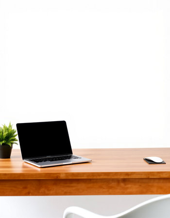 Laptop with blank screen on wood table and white wall background.