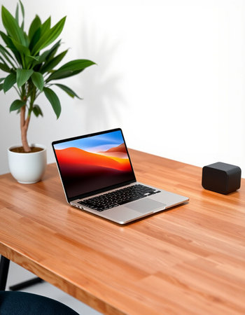laptop on wooden table with plant and speaker on white wall background