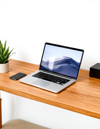 Laptop with blank screen on wooden table and white wall background.