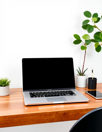 Laptop with blank screen on wooden desk and white wall background.