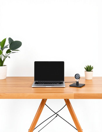 Laptop with blank screen on wooden table and white wall background.