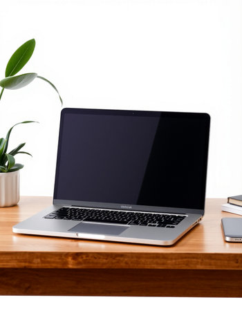 Laptop with blank screen on wooden table and white wall background.