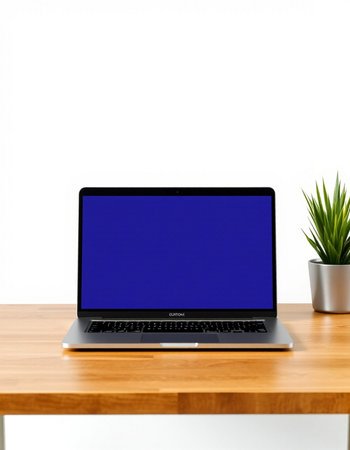 Laptop with blank blue screen on wooden table and white wall backgroundの写真素材