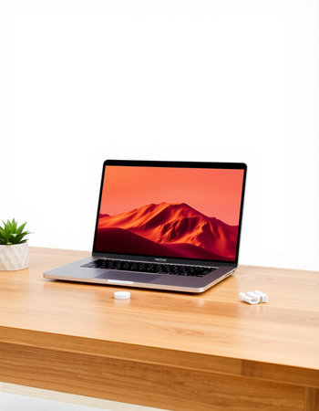 Laptop with red screen on wooden table and white wall background.