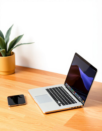 Laptop and smartphone on the wooden table with white wall background.
