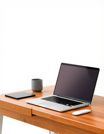 Laptop and coffee cup on wood table with white wall background.