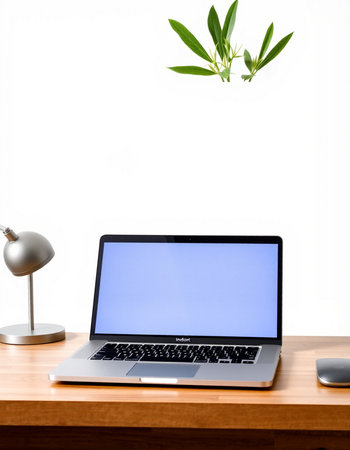 Laptop with blank screen on the wooden table and white wall background
