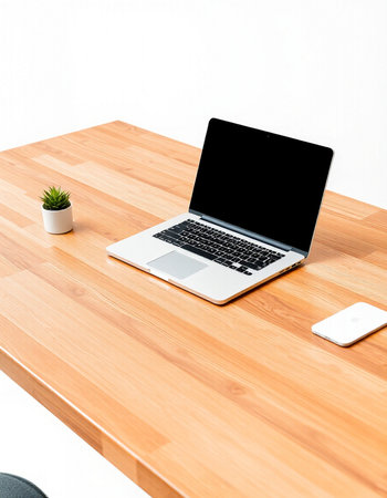 Laptop on wooden desk with smartphone and plant on white wall backgroundの写真素材