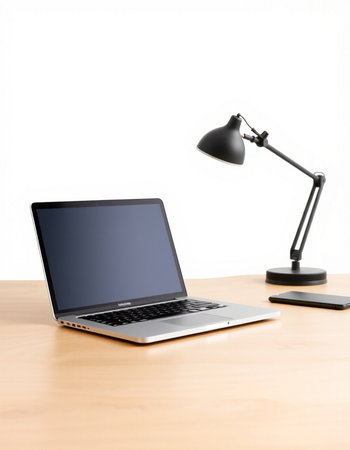 Laptop on a desk with a lamp and a white background.