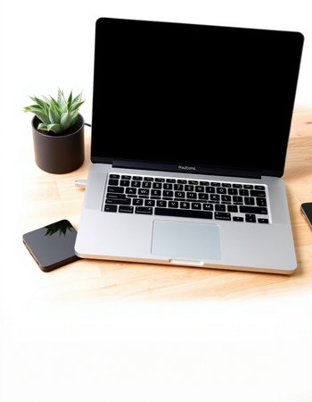 Laptop with blank screen on a wooden desk with smartphone and plant