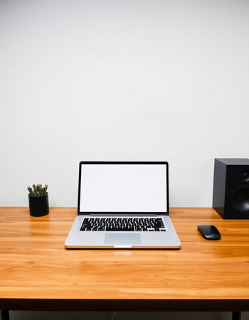 Laptop with blank screen on wooden desk in front of white wallの写真素材