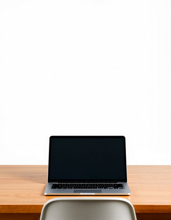 Laptop with blank screen on wood table and white wall background.
