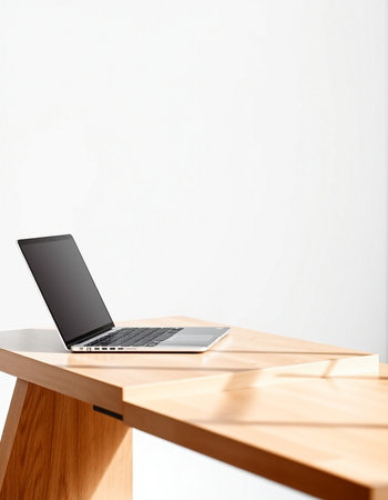 Laptop on a wooden table with a white wall in the background