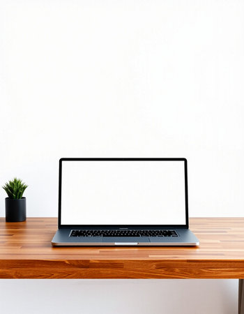 Laptop with blank screen on wooden table and white wall background.