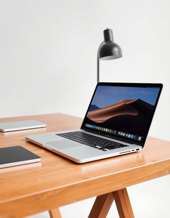 laptop and smart phone on wooden table with white wall in background