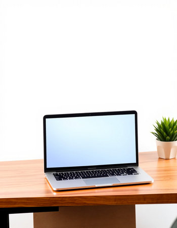 Laptop with blank screen on wooden table and white wall background.