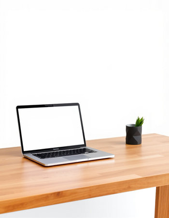 Laptop with blank screen on wooden table and white wall background.