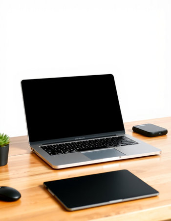 Laptop with blank screen on wooden table and white wall background.
