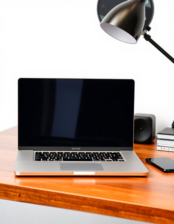 Laptop on wooden table with lamp and books on white background.