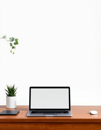 Laptop with blank screen on wooden table and white wall background.
