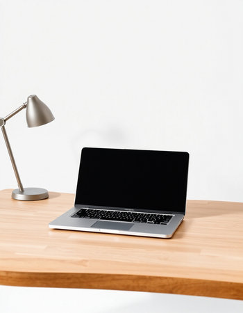 Laptop with blank screen on wooden table and lamp on white wall backgroundの写真素材