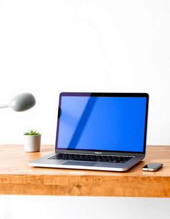 Laptop with blue screen on wood table and white wall background.の写真素材
