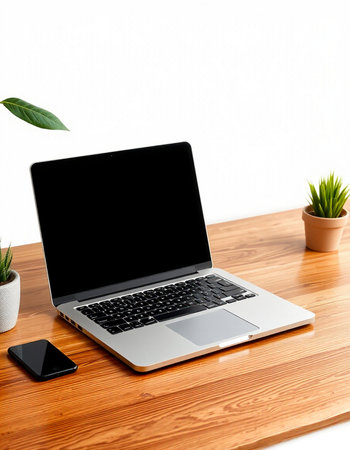 Laptop with blank screen on wooden table and white wall background.