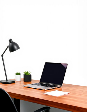 Laptop on the desk with black lamp and plant on white wall background