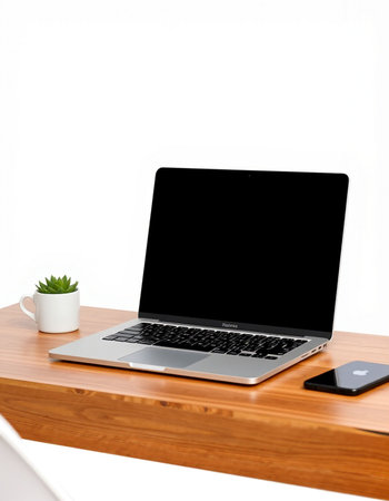 Laptop with blank screen on wood table and white wall background.