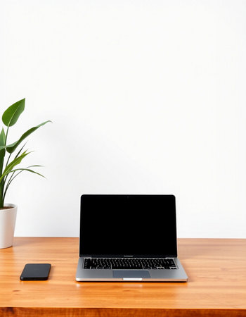Laptop with blank screen on wooden table and white wall background.