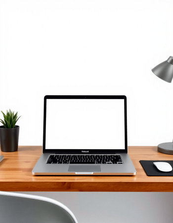 Laptop with blank screen on wooden table and white wall background.