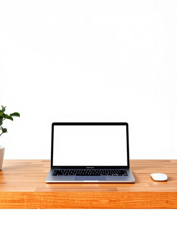 Laptop with blank screen on wooden table and white wall background.