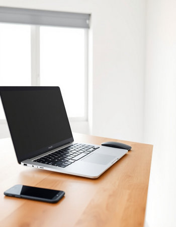 Laptop with blank screen on wooden desk in modern office, stock photo