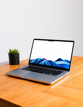 Laptop with blank screen on wooden desk in front of white wallの写真素材