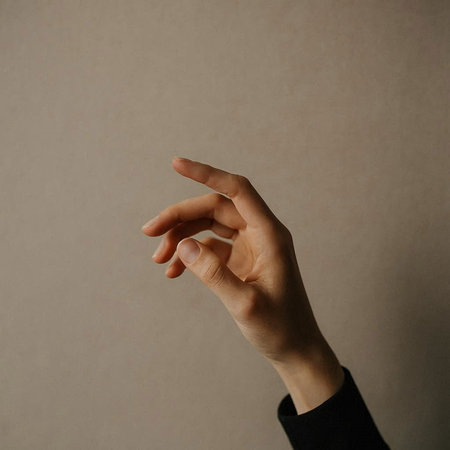 Female hand gesturing with fingers on gray background. Close up.