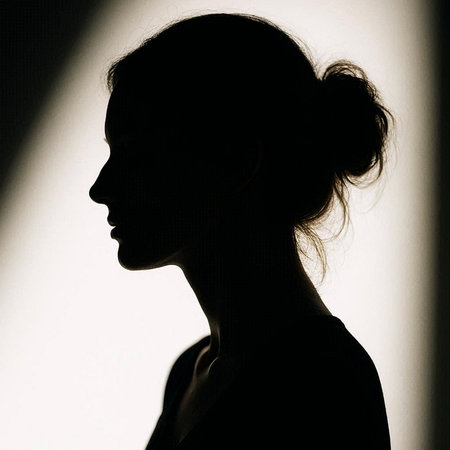 Silhouette of a beautiful young woman in a dark room.