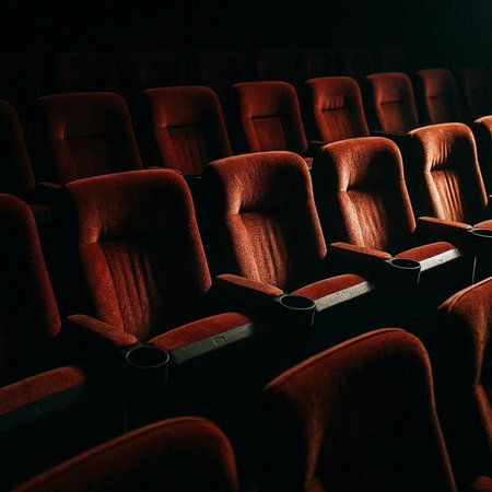 Cinema auditorium with red seats and chairs in the dark