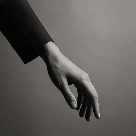 Female hand in black suit on a gray background. Studio shot.