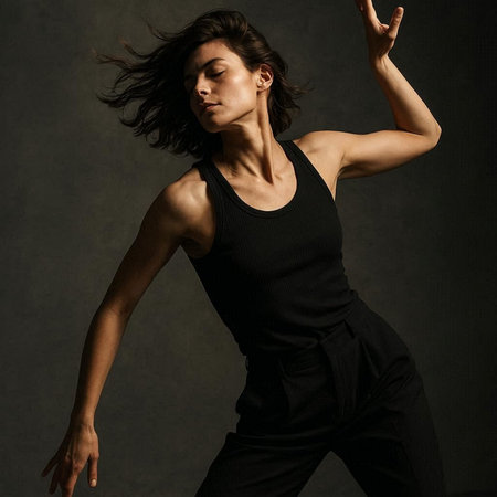 Young beautiful dancer posing in studio on a dark background. Toned.