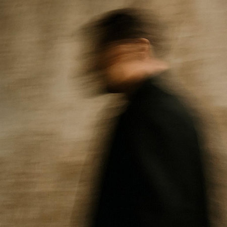 Blurred image of a man in a black coat. Motion blur.
